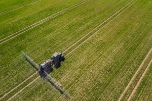 tractor spraying herbicides on field, Tractor Spraying Chemicals on Field - GMO Crops